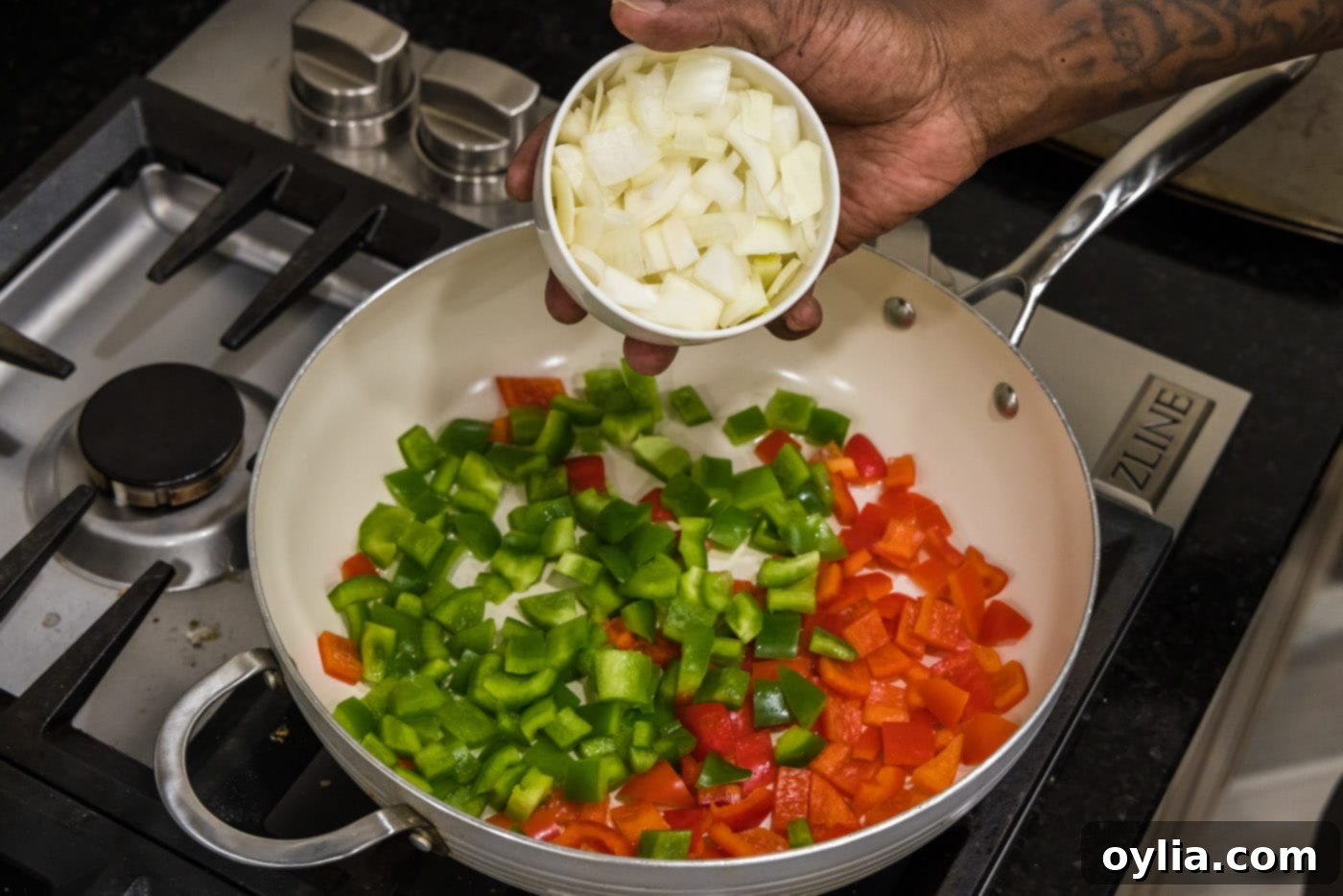 adding onion to bell peppers in a skillet