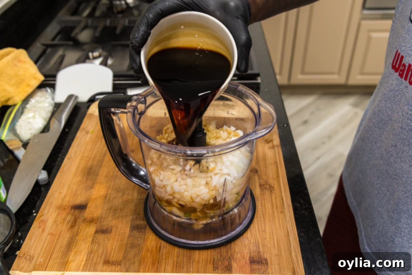 Pouring soy sauce into a food processor with other Korean marinade ingredients, including garlic, onion, and pears.