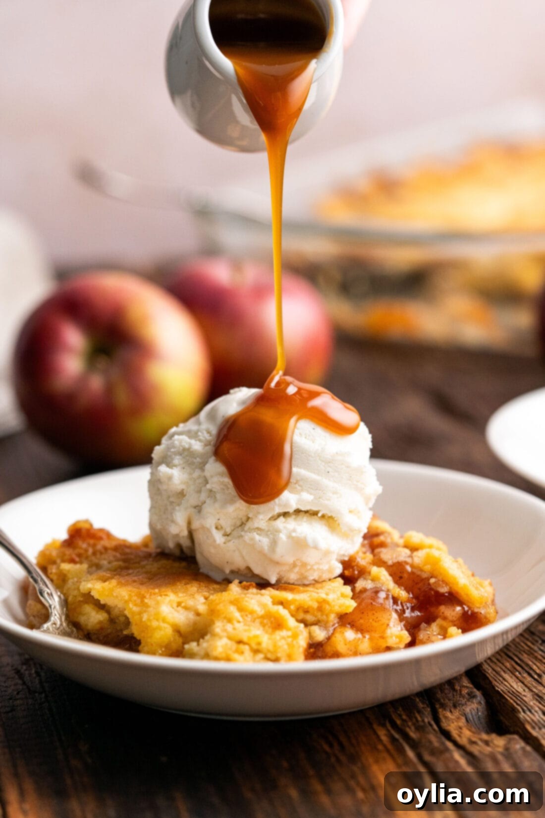 One Pan Caramel Apple Bliss 2 Caramel sauce being drizzled over Caramel Apple Dump Cake topped with ice cream