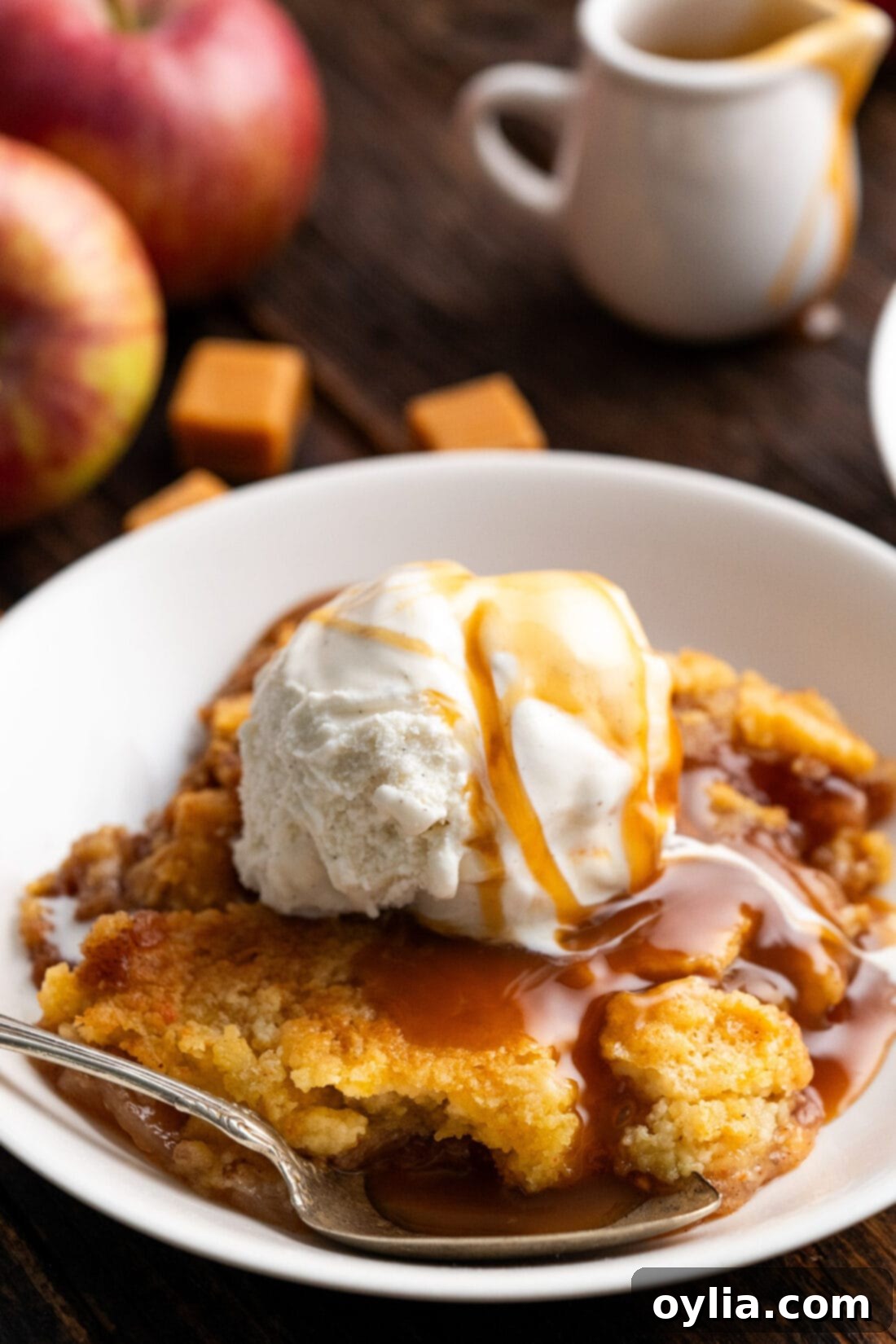 One Pan Caramel Apple Bliss 13 Caramel Apple Dump Cake in a bowl topped with ice cream and caramel sauce