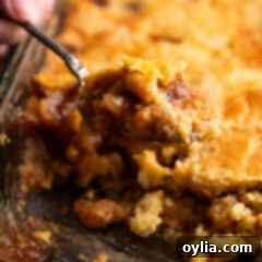 One Pan Caramel Apple Bliss 14 Close up photo of a spoonful of Caramel Apple Dump Cake being lifted out of the pan