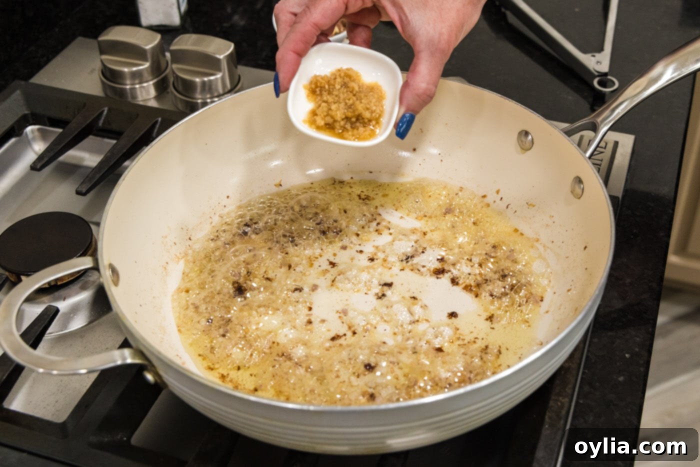 adding garlic to skillet with shallots and oil