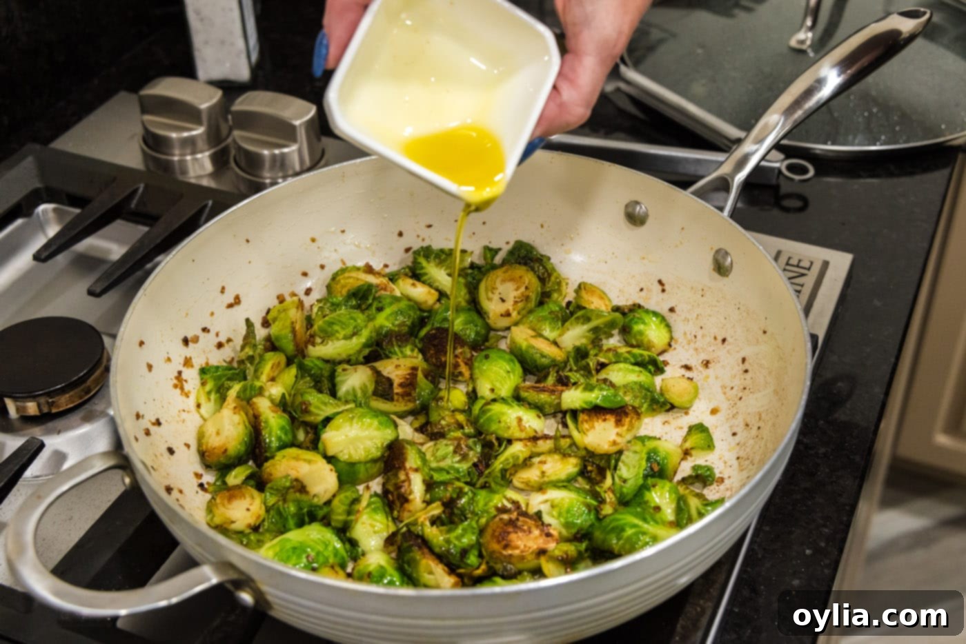 pouring oil into brussels sprouts in a skillet