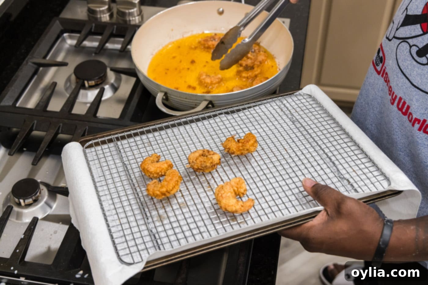 tongs removing fried shrimp from oil