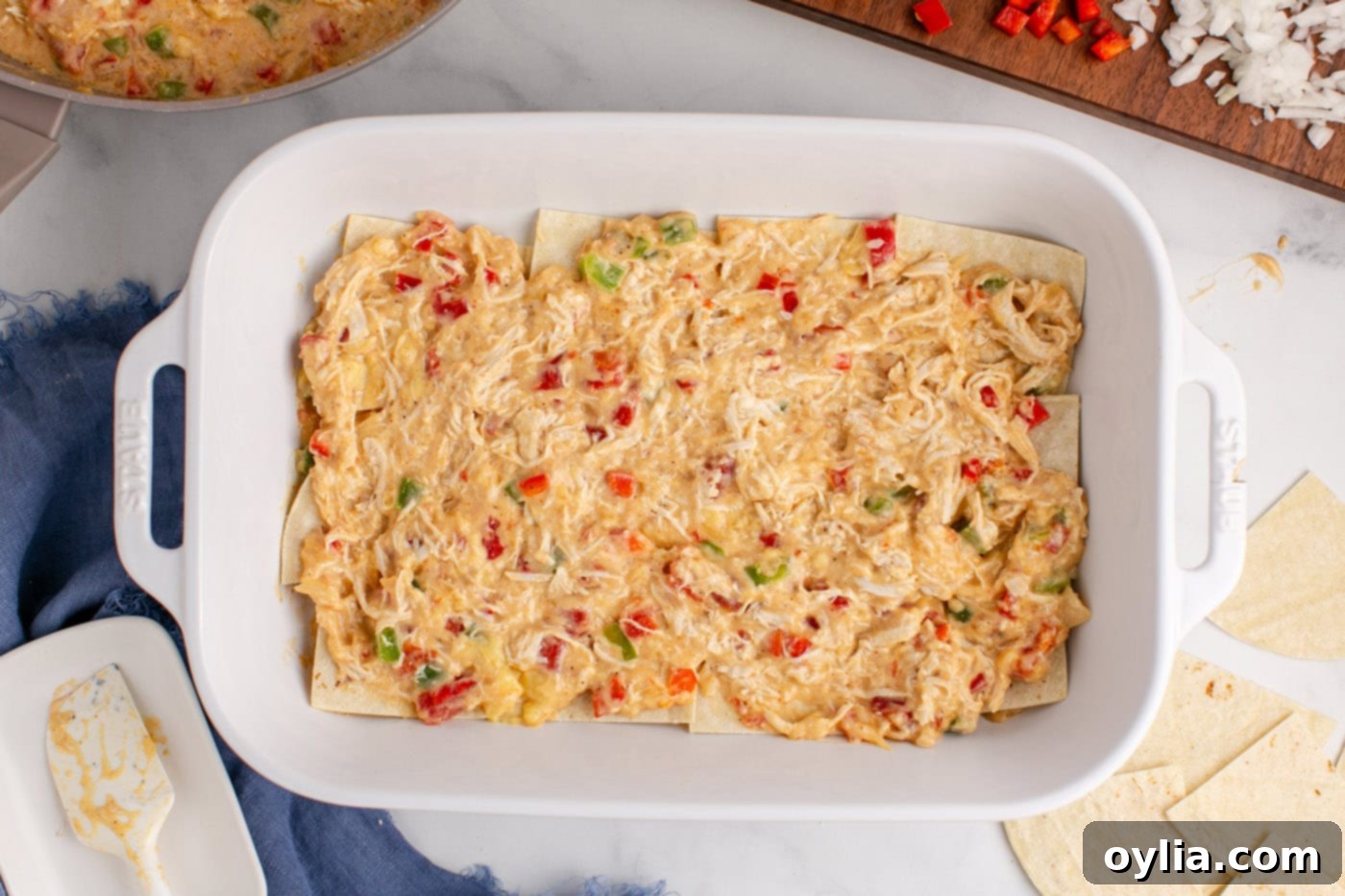 chicken and sauce mixture layered over tortillas in a dish