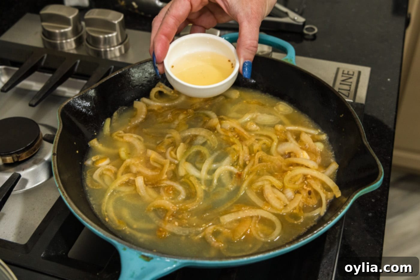 pouring rice vinegar into skillet with onions and chicken broth