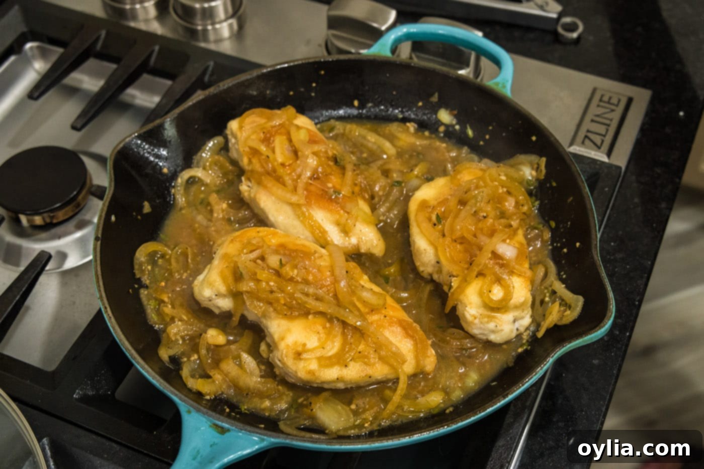 chicken breasts in a skillet with onion thyme sauce