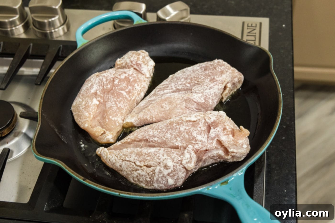 searing flour coated chicken breasts in a skillet