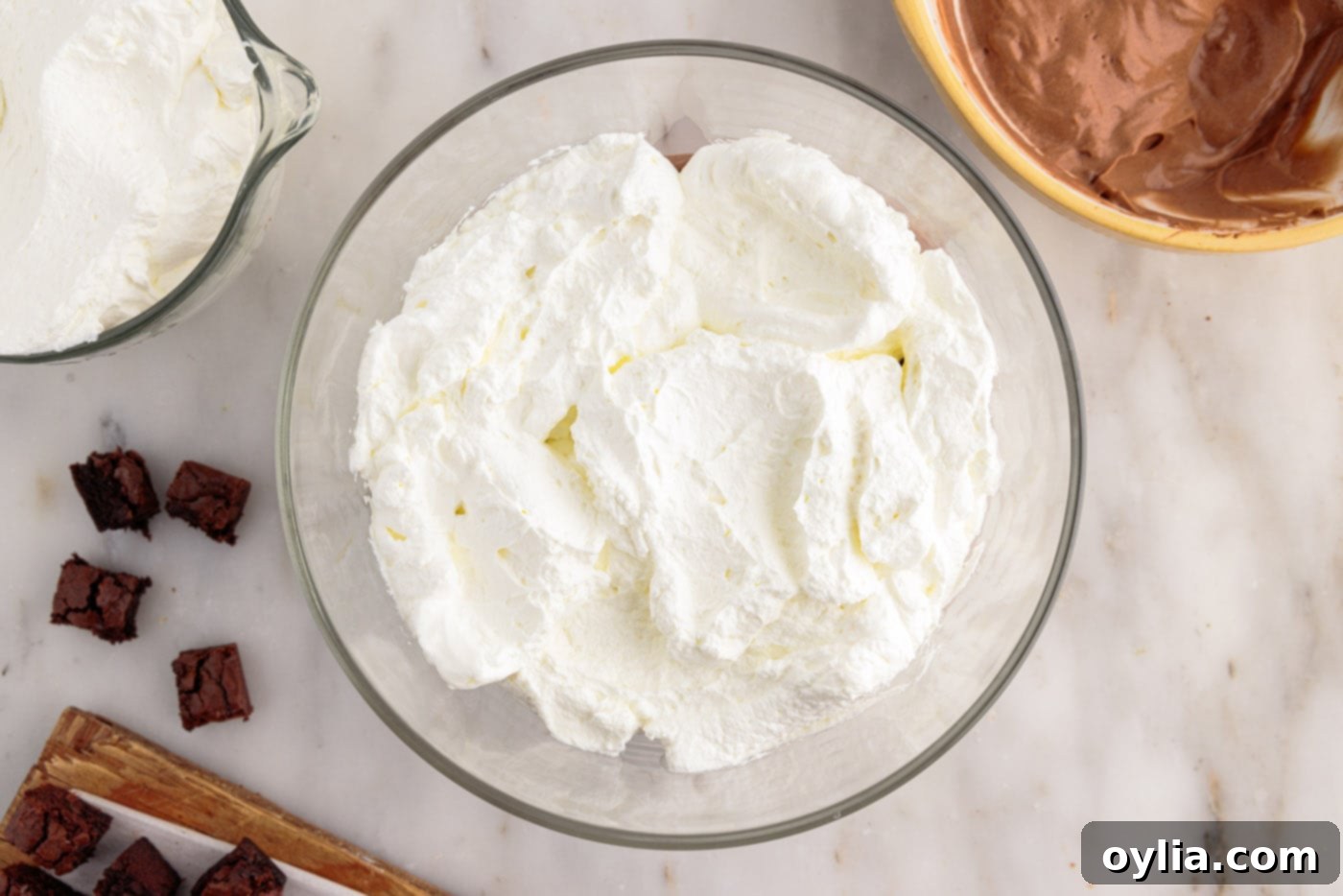 layer of whipped cream on top of chocolate pudding and brownie pieces