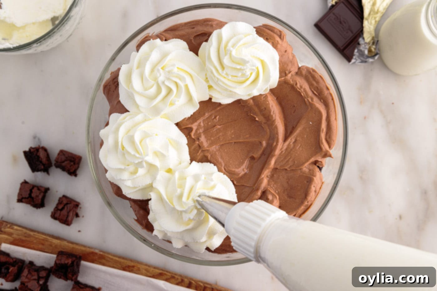 piping whipped cream on top of brownie trifle