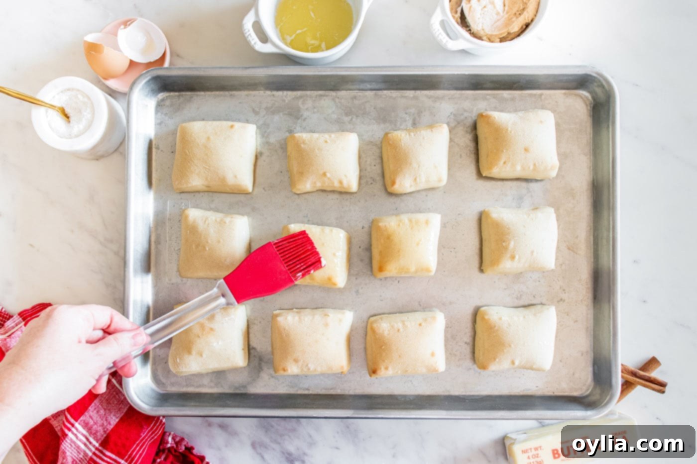 brushing texas roadhouse rolls with melted butter on a baking sheet before serving