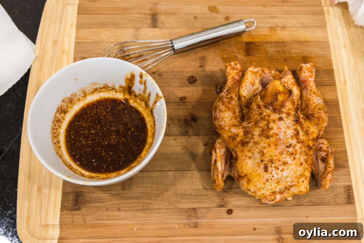 adding wet rub to cornish hen on a cutting board
