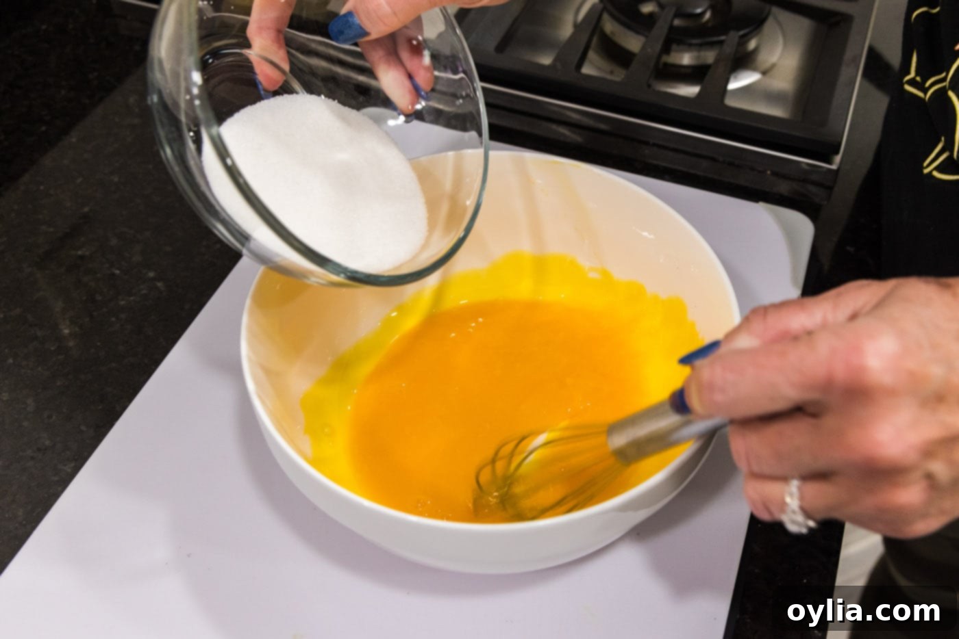 adding sugar to egg yolks in a bowl