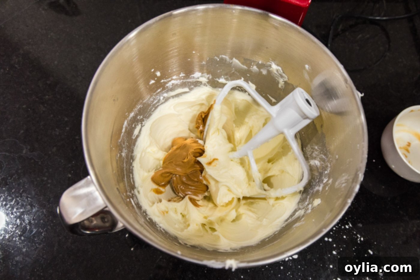 peanut butter added to cream cheese frosting in a bowl of a stand mixer