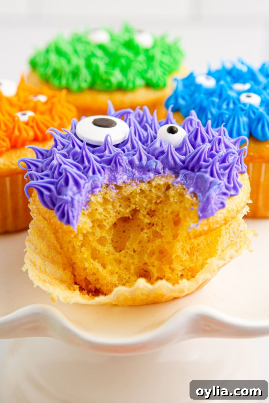 Close-up photo of a bite taken out of a Monster Cupcake, revealing fluffy colored frosting and a candy eye.