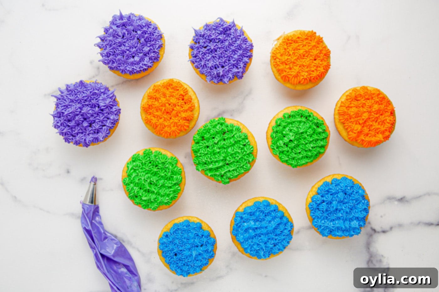Colorful piped frosting on top of cooled cupcakes.