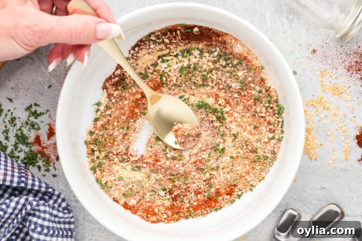 spoon mixing spices together in a bowl to create a uniform All Purpose Seasoning blend