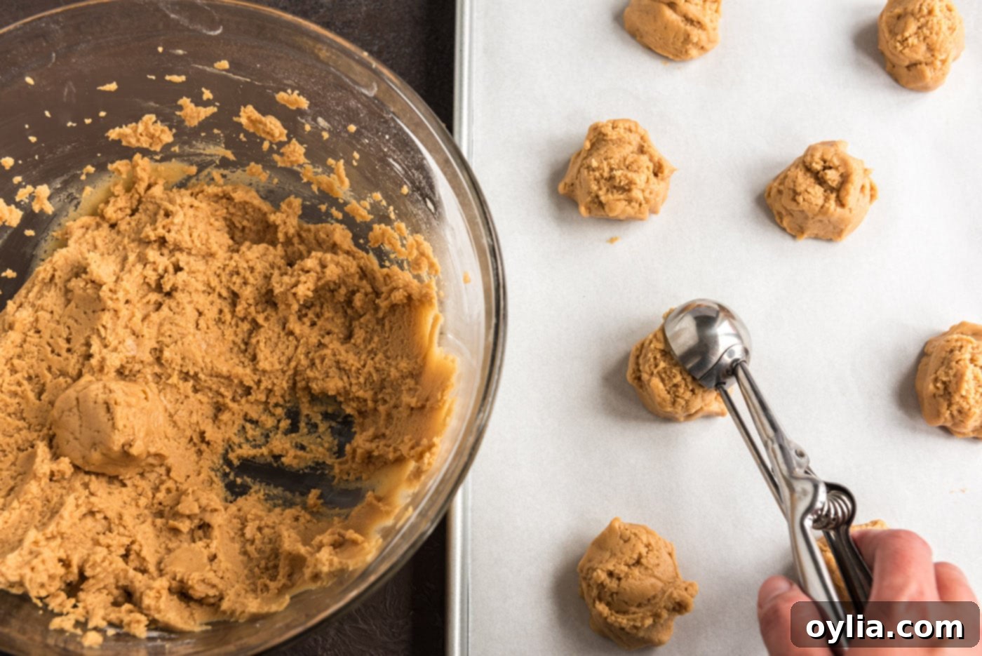 Scooping portions of peanut butter cookie dough onto a baking sheet, evenly spaced for baking.