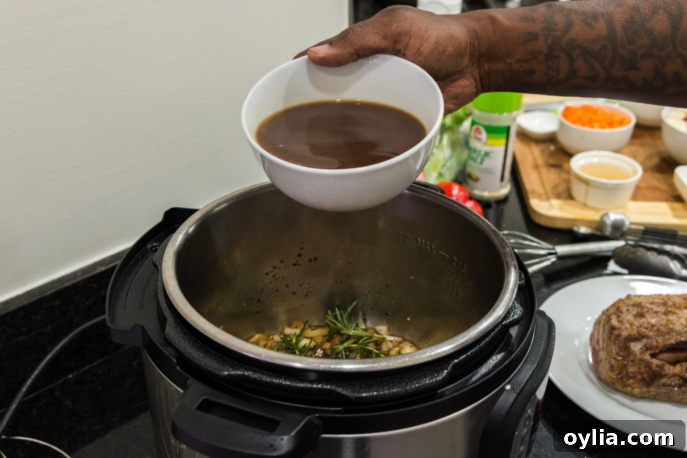 Beef broth being poured into the Instant Pot with the sautéed aromatics, forming the rich liquid base for the roast.