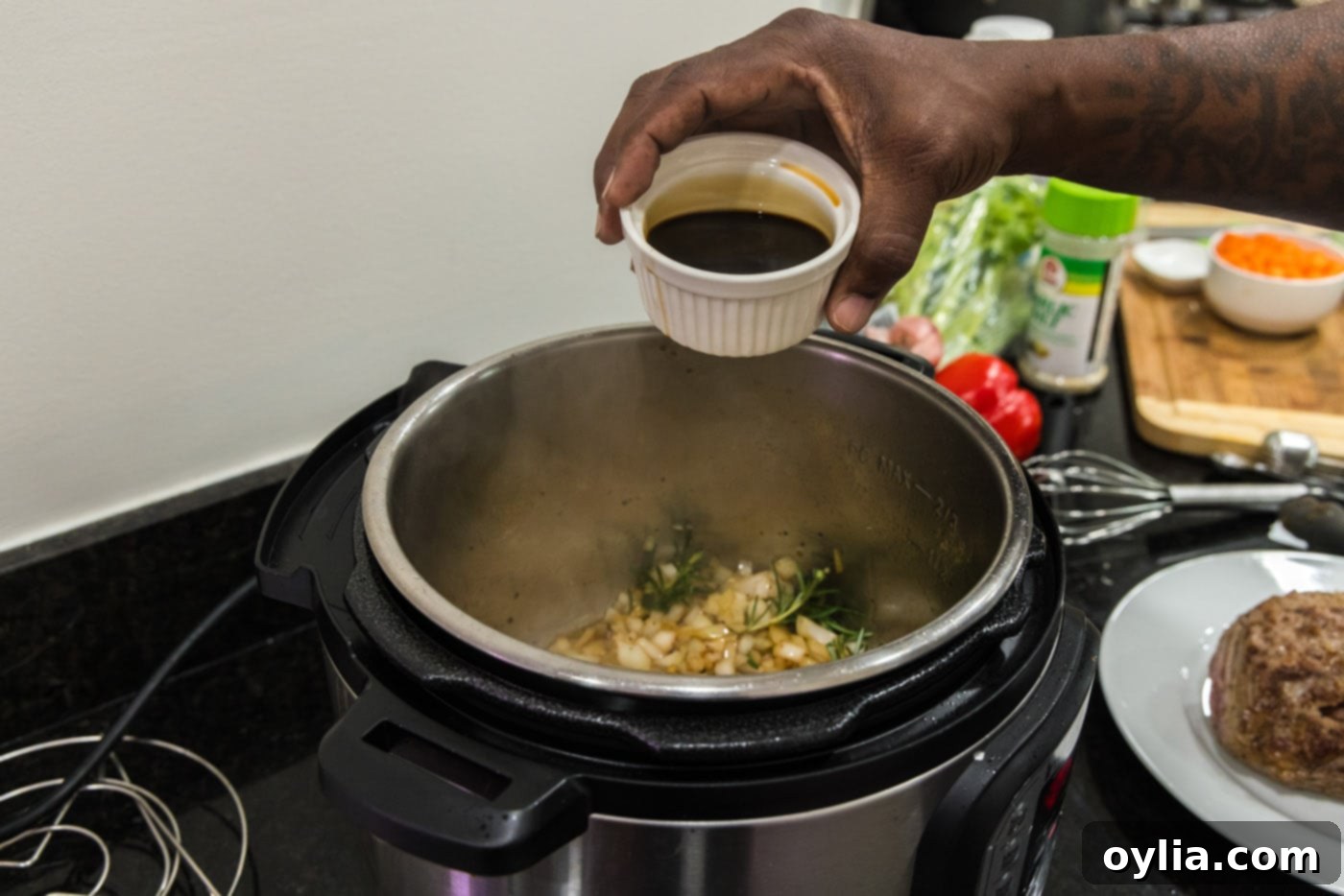 Low sodium soy sauce being poured into the Instant Pot, adding a layer of umami to the onion and garlic mixture for the roast.
