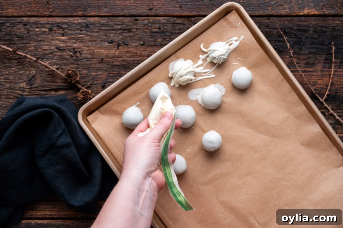 Drizzling melted white chocolate over a white-coated Oreo truffle to create mummy bandages.