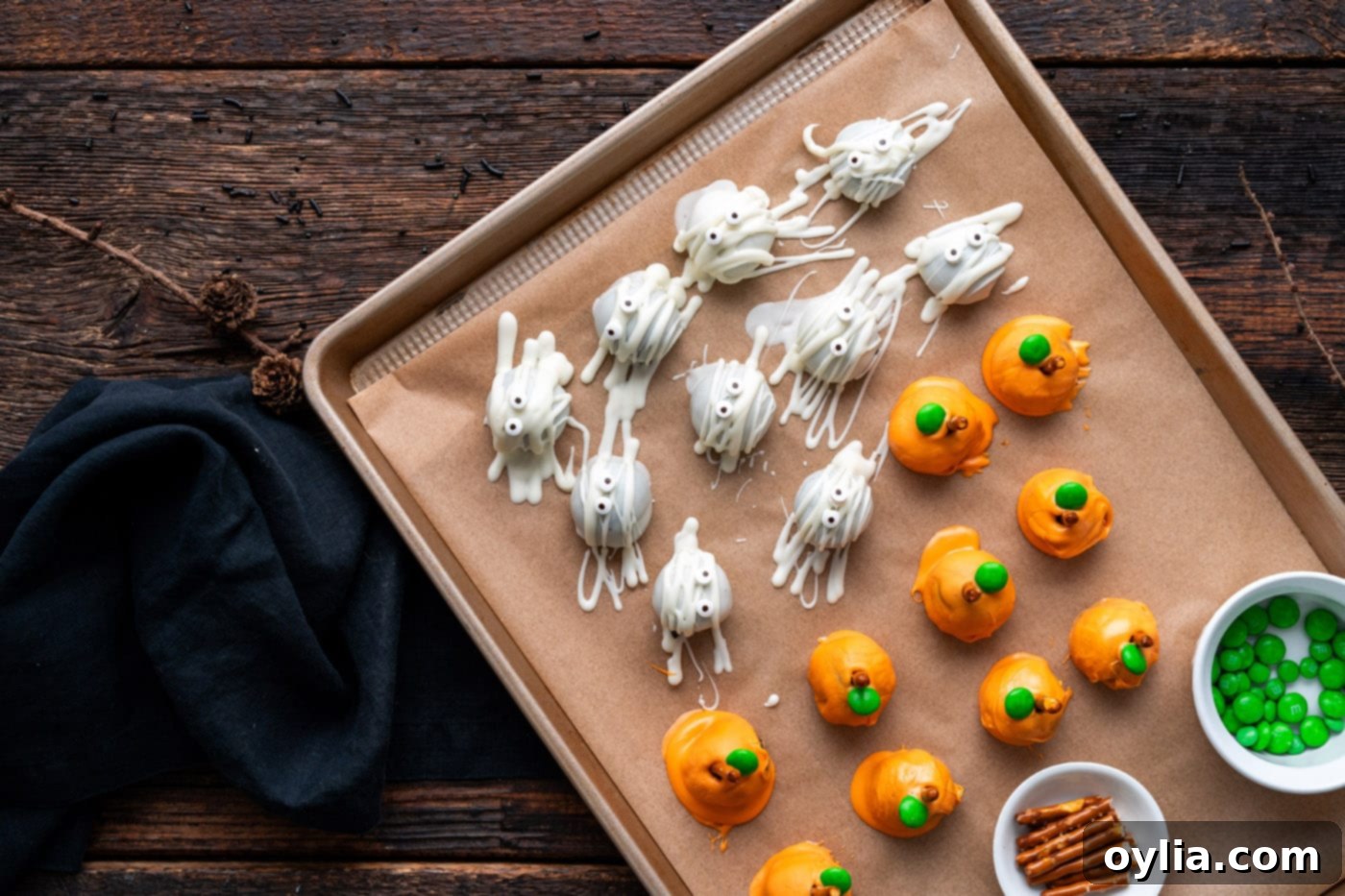 Pumpkin Oreo truffles arranged on a baking tray alongside mummy truffles, showcasing a variety of Halloween designs.