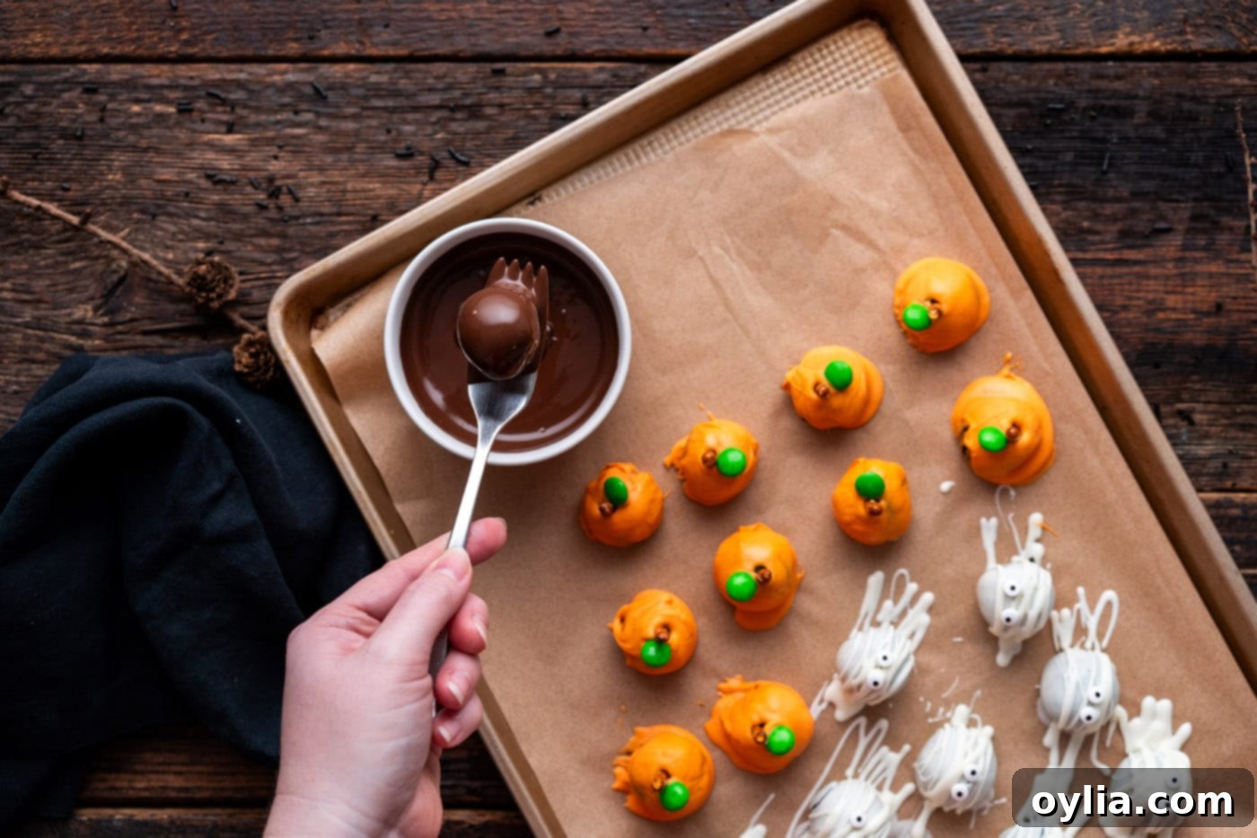Dipping an Oreo truffle into rich melted chocolate, ensuring an even and glossy coating.