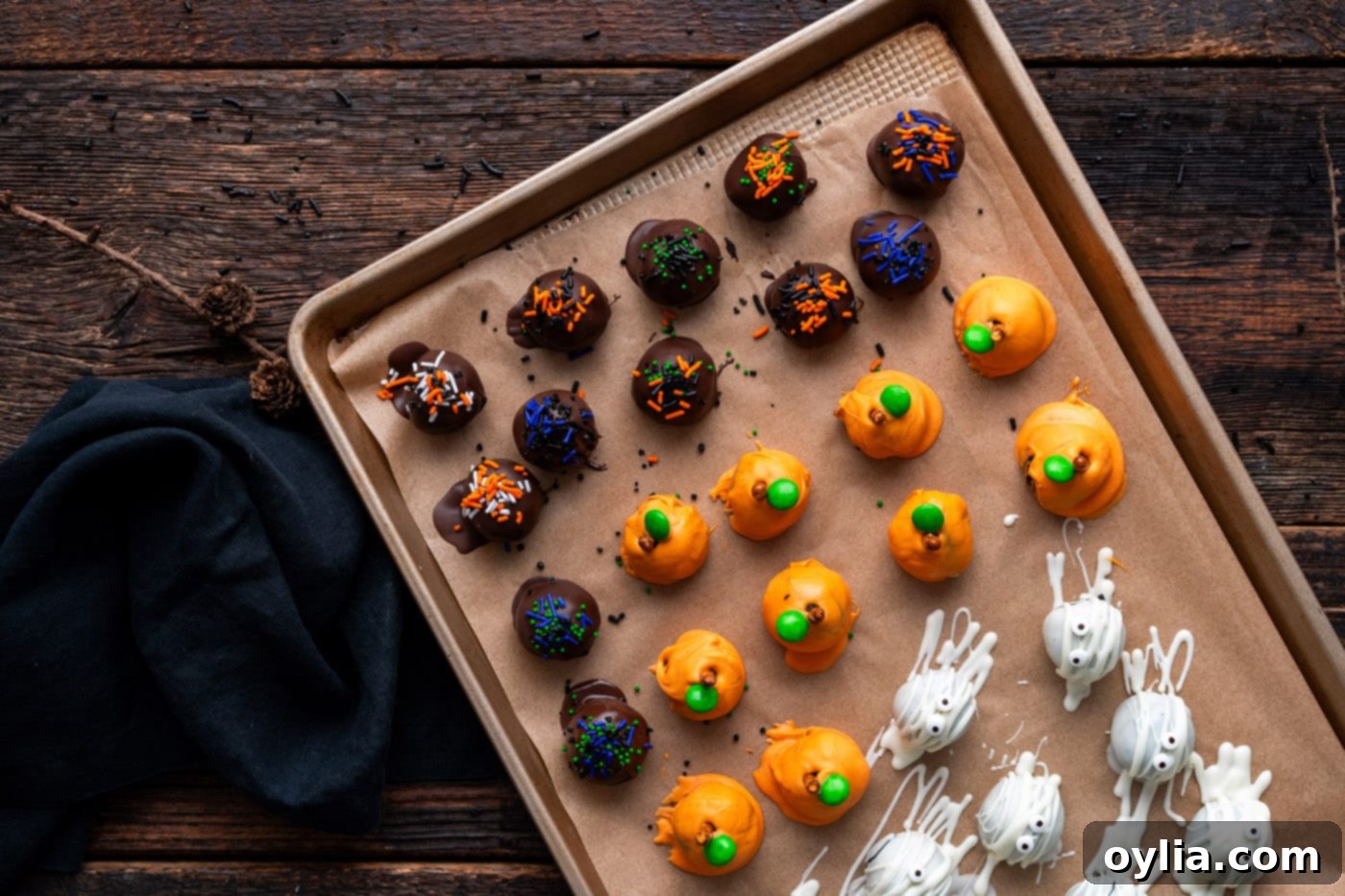 Halloween Oreo truffles on a baking sheet, freshly covered with colorful Halloween sprinkles.