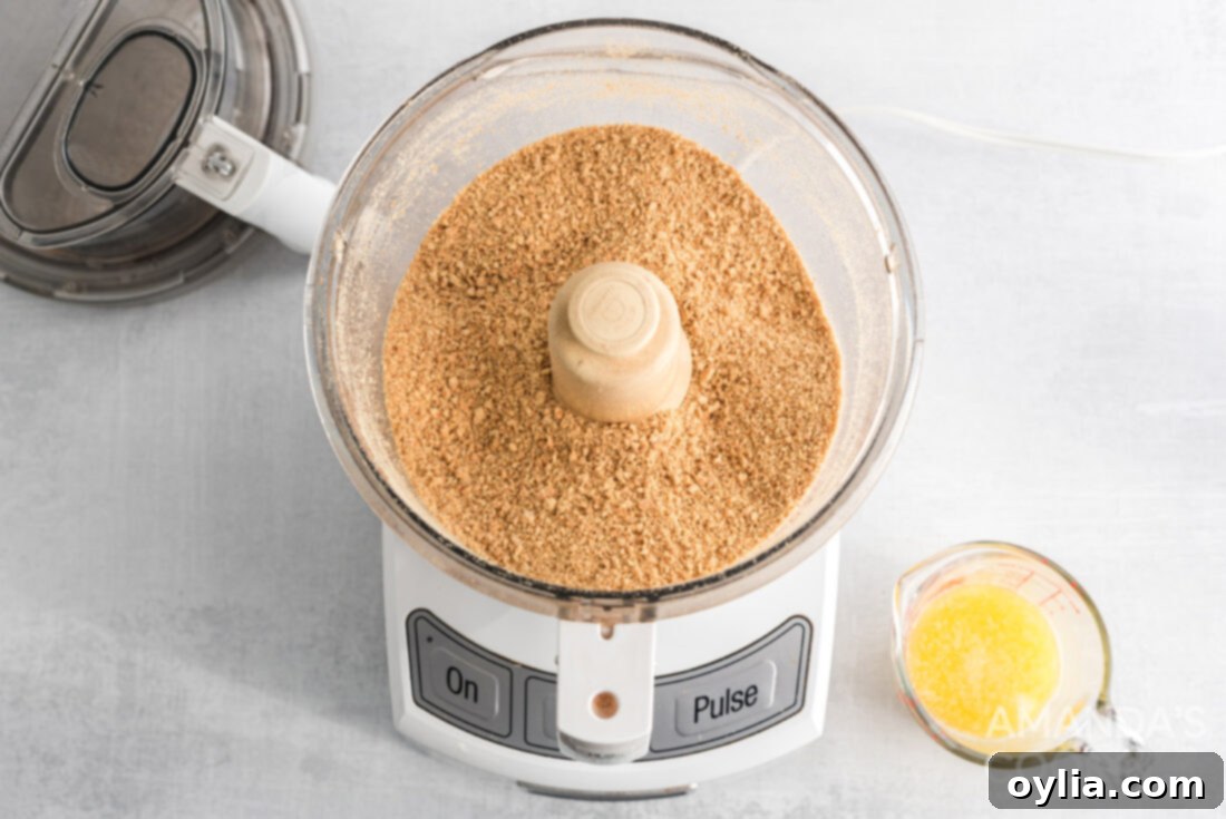 Graham cracker crumbs being processed to a fine consistency in a food processor, ready for the crust.