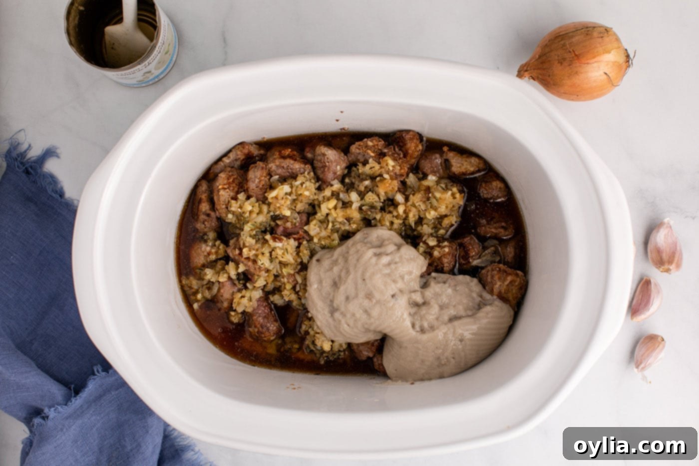 cream of mushroom soup added to crockpot with beef stew meat and onions