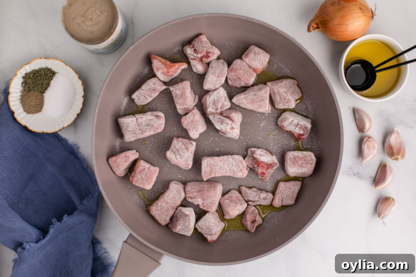 flour coated beef cubes searing in a skillet