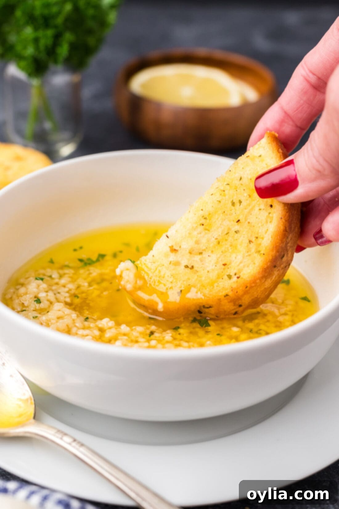 Piece of bread being dipped into Garlic Butter Sauce
