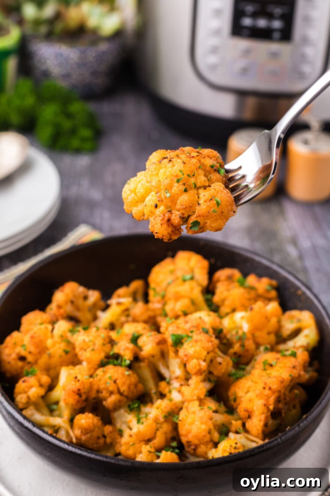 Piece of Instant Pot Cauliflower on a fork held above a bowl of Instant Pot Cauliflower