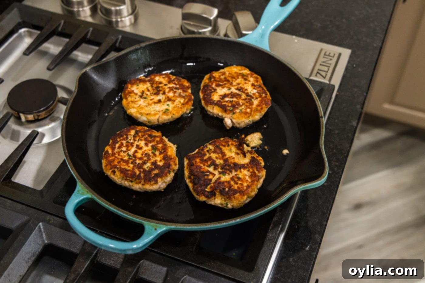 Cooked salmon burgers with a perfect golden crust resting in the skillet