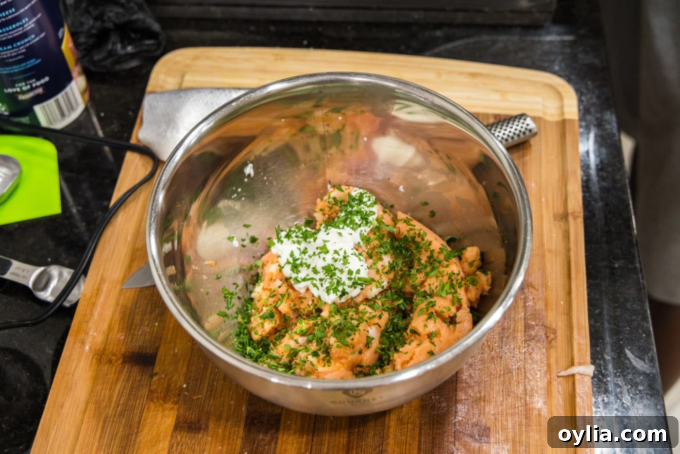 Adding Greek yogurt to the ground salmon mixture in a bowl