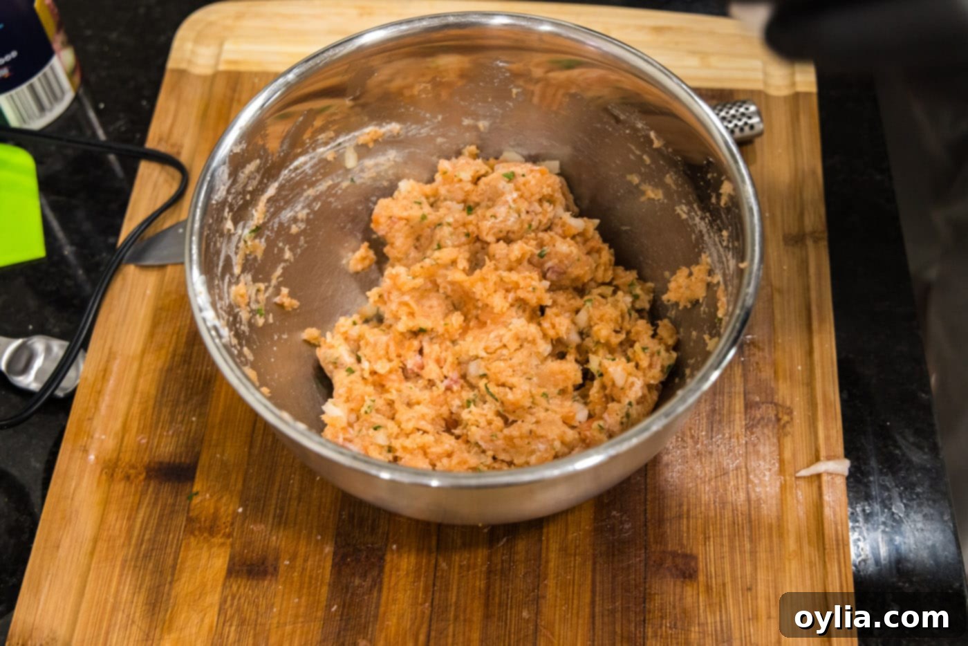 Close up of a bowl with ground salmon mixture formed into four patties