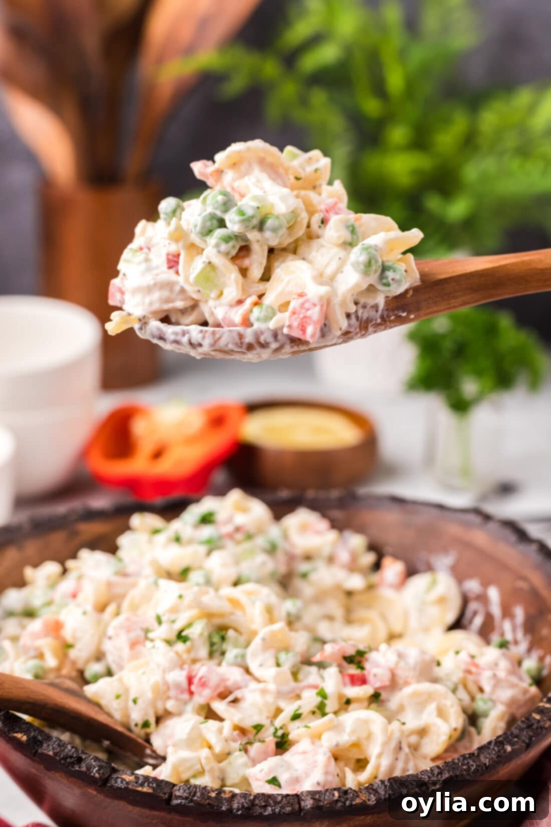 Spoonful of Shrimp Pasta Salad lifted above a bowl of Shrimp Pasta Salad