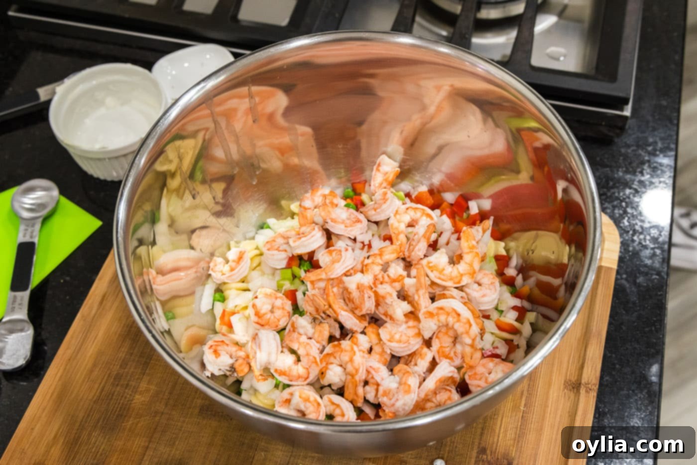cooked shrimp added to bowl of pasta and veggies