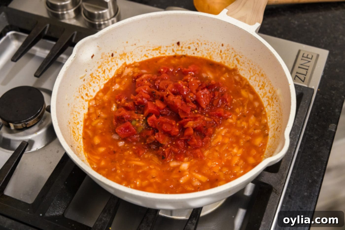 adding crushed tomatoes to skillet with vodka and onion mixture