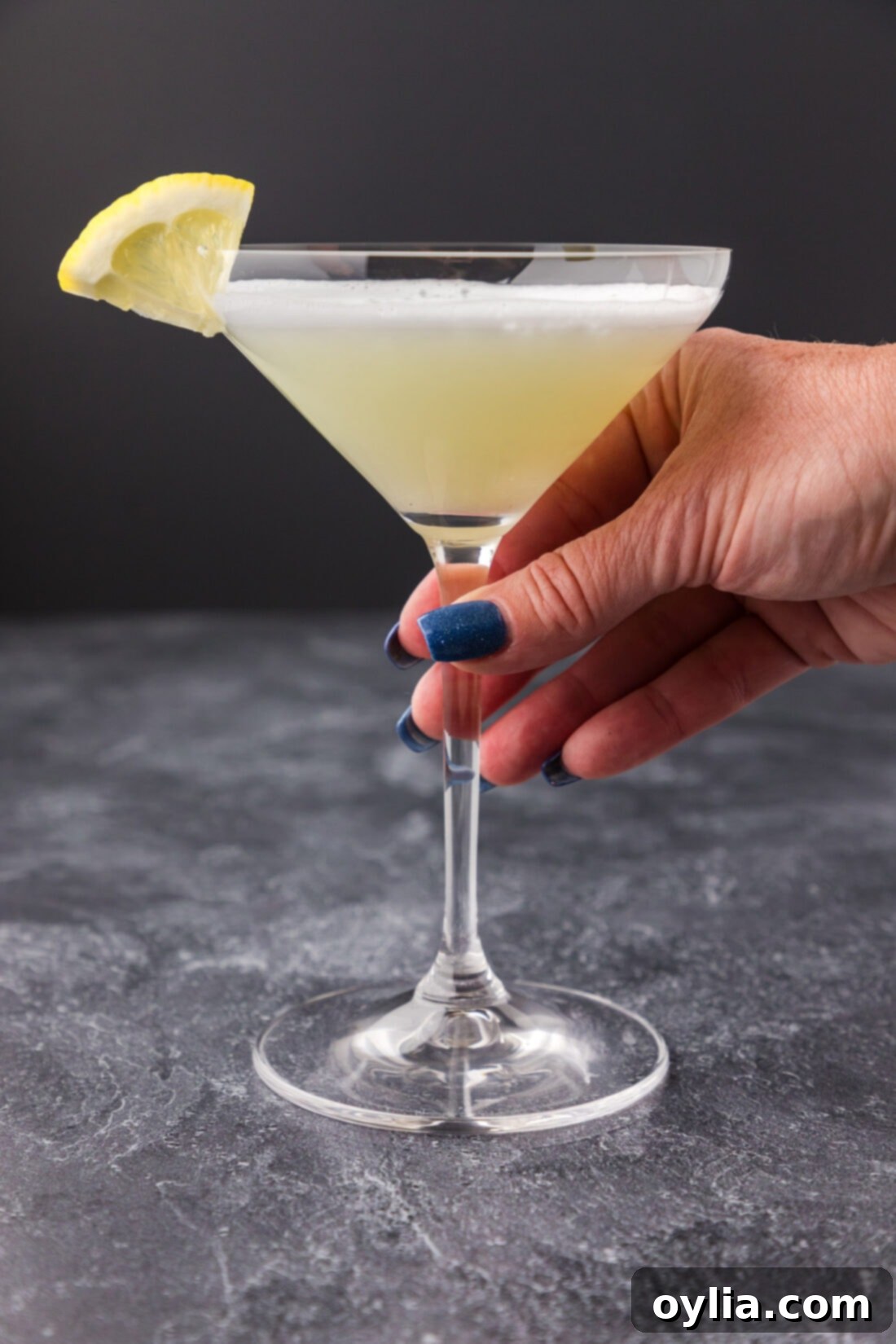 A hand holding a beautifully presented White Lady Cocktail with its signature foam