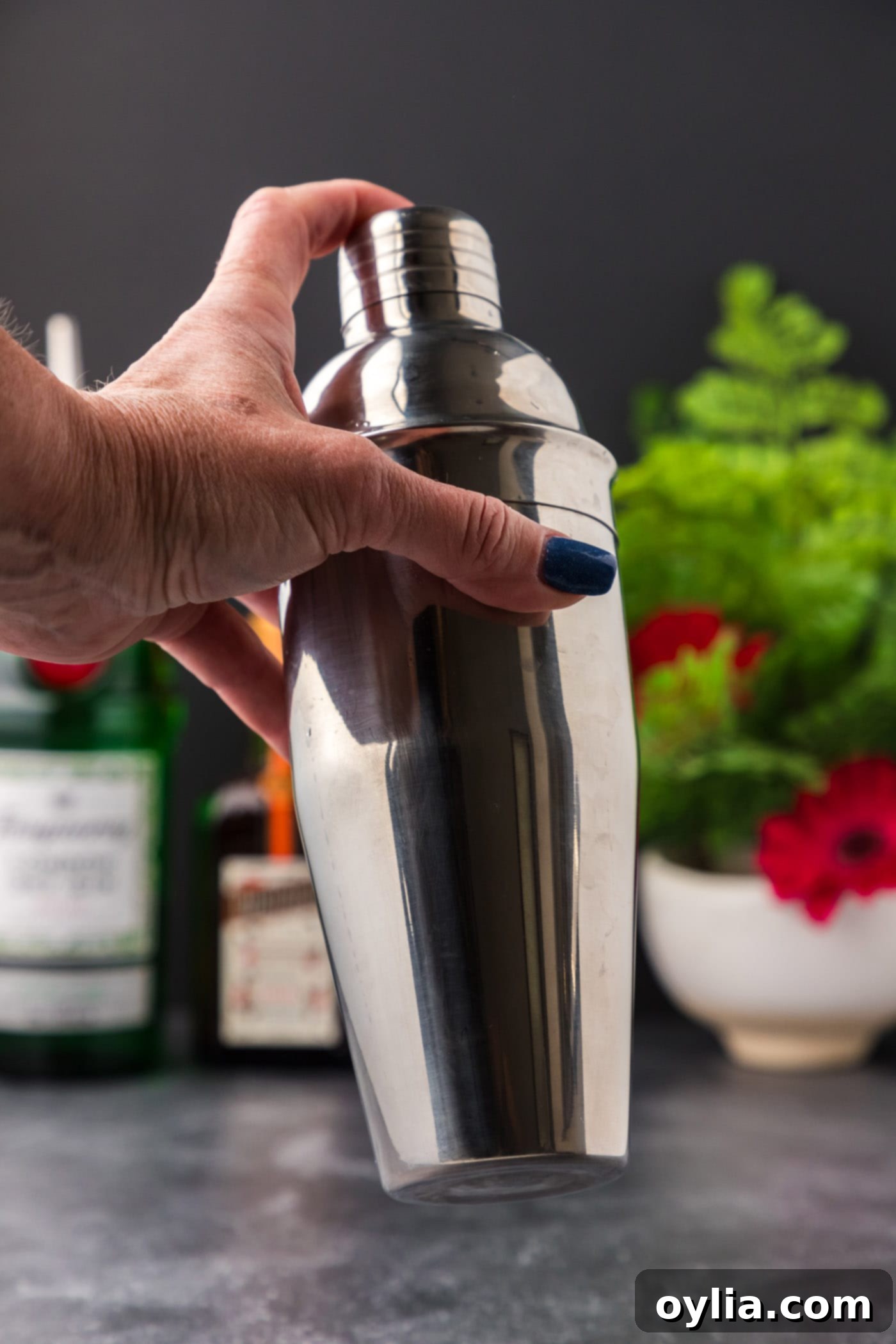 Vigorously shaking a cocktail shaker during the dry shake phase for a White Lady Cocktail