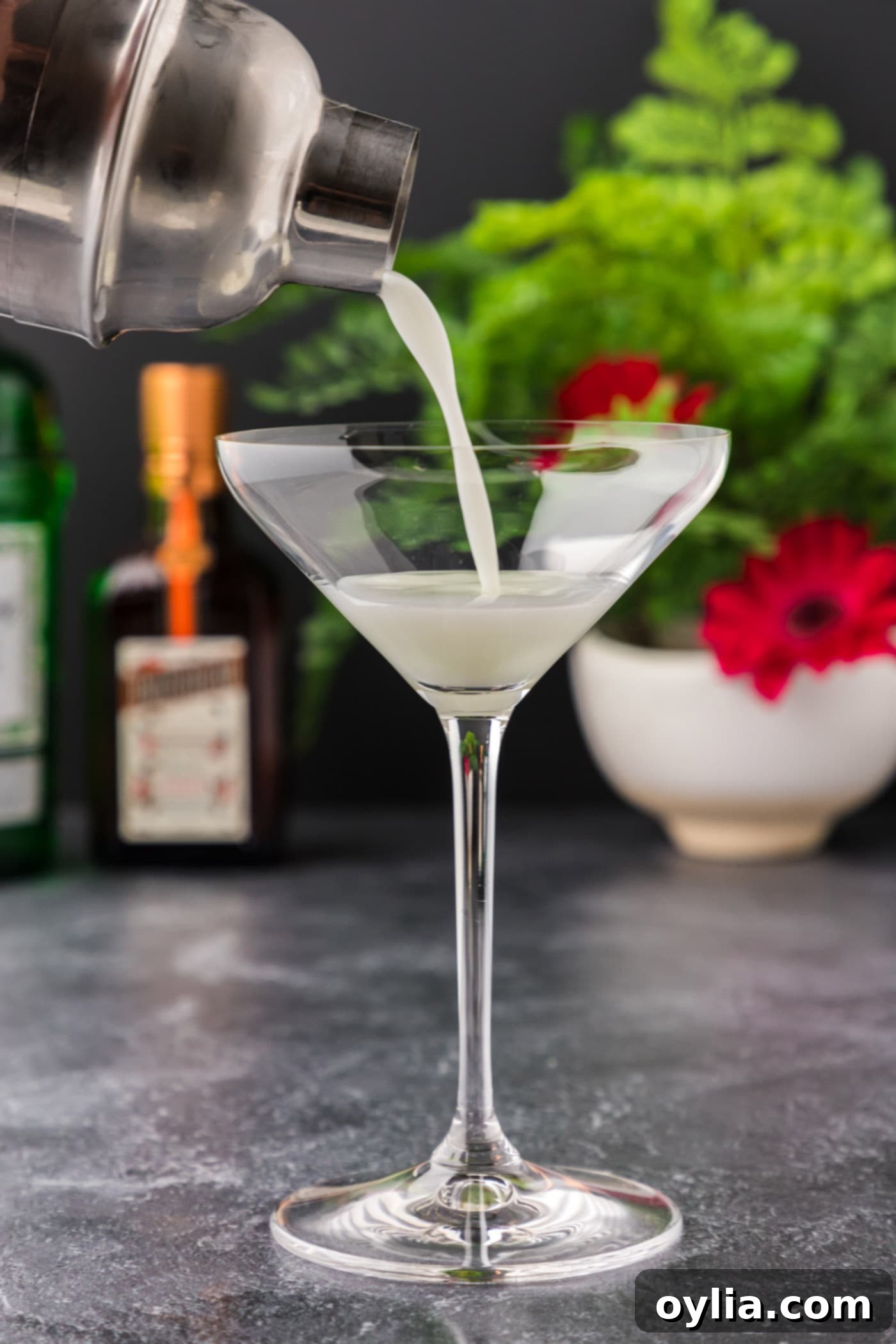 Straining a frothy White Lady Cocktail into an elegant martini glass