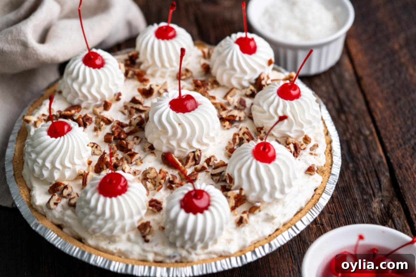 Fully garnished Million Dollar Pie with elegant piped Cool Whip, bright maraschino cherries, and chopped pecans.