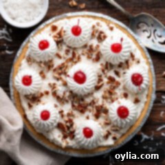 Overhead photo of a Million Dollar Pie, garnished with Cool Whip rosettes, cherries, and pecans.