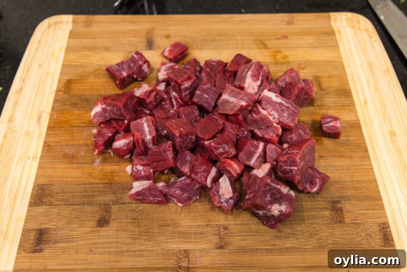 Flank steak expertly cubed and ready for cooking on a cutting board.
