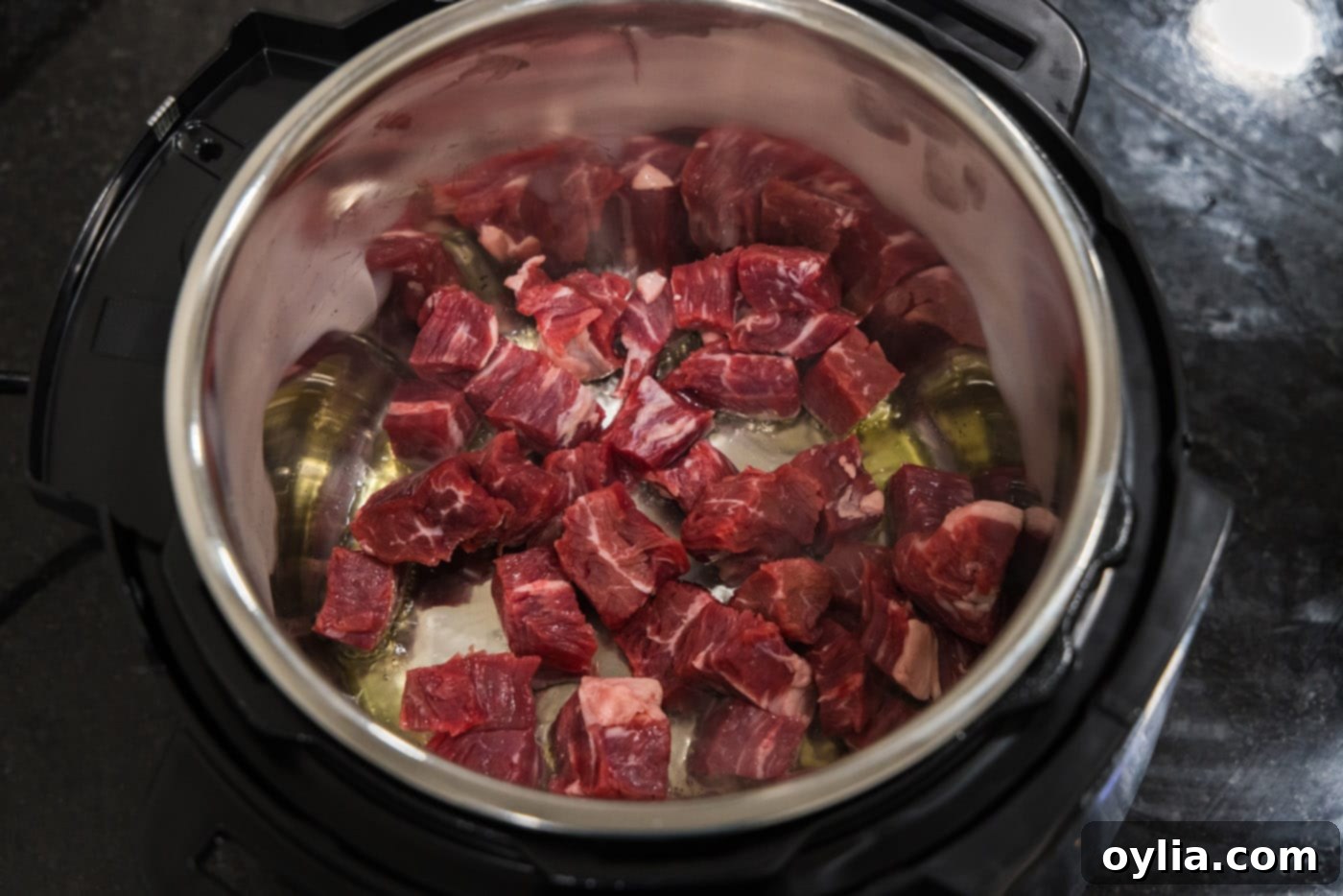Flank steak pieces browning in olive oil in the Instant Pot on the sauté setting.