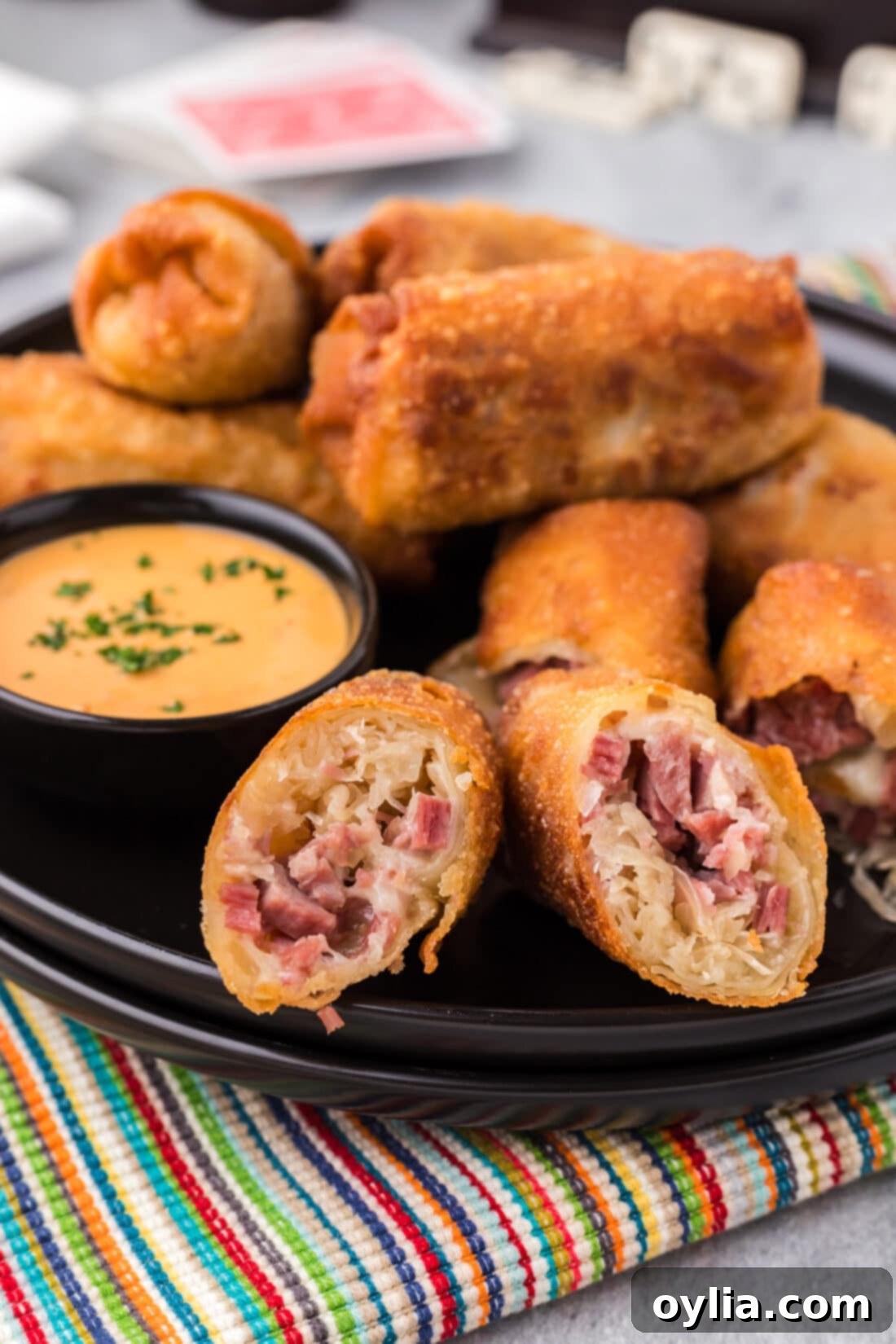 Close up photo of Reuben Egg Rolls on a plate with a bowl of thousand island dressing