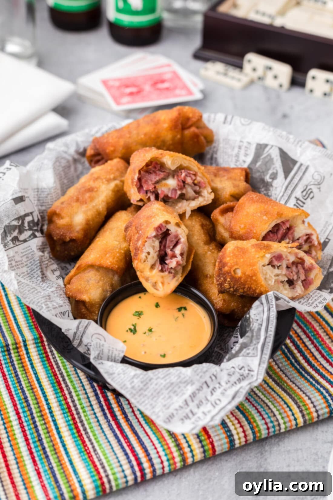 Reuben Egg Rolls cut in half resting in a basket with sauce