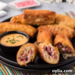Close up photo of a Reuben Egg Roll cut in half on a plate with more rolls in the background