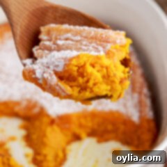 Spoonful of Carrot Souffle held above a dish of Carrot Souffle